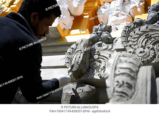 16 April 2019, Berlin: A man models the figure of a temple bearer on the construction site of the Hindu temple on the Hasenheide