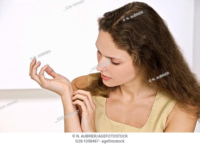 young woman scratching the inside of her wrist  because of an itching sensation