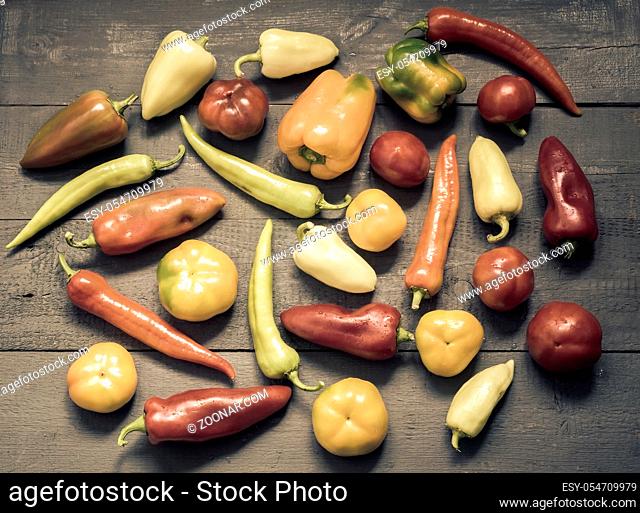 On the painted wooden background of a variety of color and shape of the fruits of bell peppers of different varieties. Top view, negative space