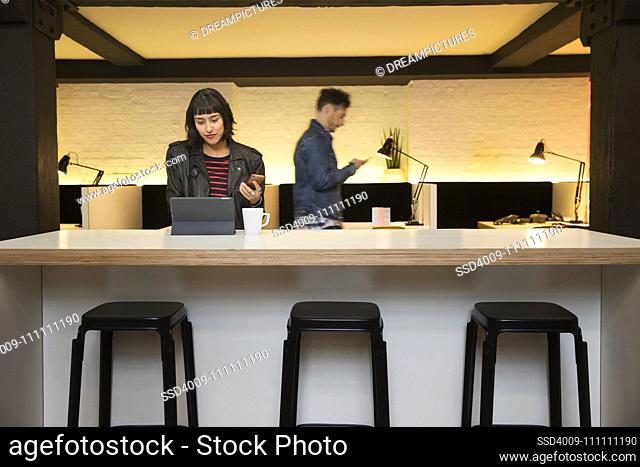 woman sitting at counter checking her phone in co-working space