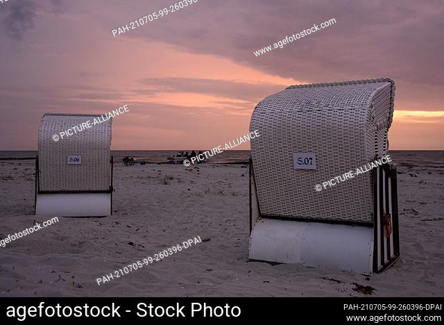 24 June 2021, Mecklenburg-Western Pomerania, Hiddensee: Between two beach chairs, holidaymakers can be seen sitting at a table and enjoying the sunset