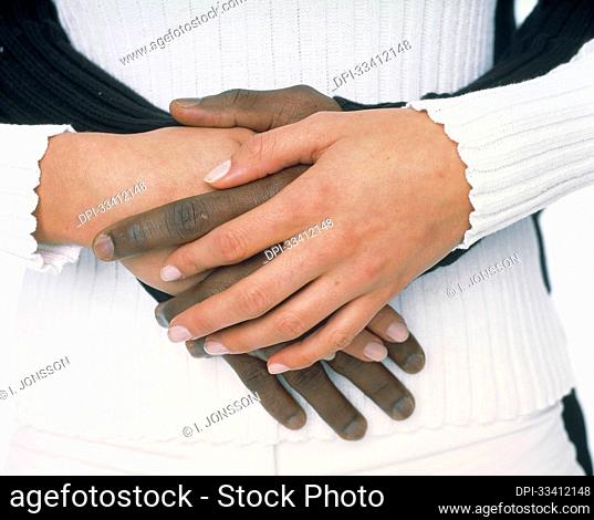 Hands of a caucasian female and african-american male intertwined; Studio
