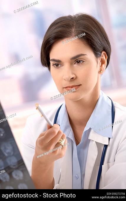 Female doctor working on diagnosis, examining x-ray in office