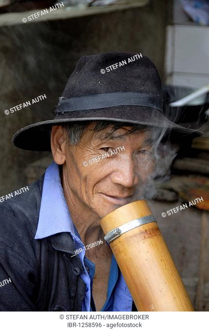 Portrait, ethnology, man of the Hani ethnic group wearing hat, smoker, smoking hookah, bong, near Xinji, Yuanyang, Yunnan Province, People's Republic of China
