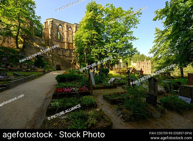 PRODUCTION - 06 July 2023, Saxony, Oybin: View across the cemetery to the remains of the fortress and the Oybin monastery in the spa town of the same name on...