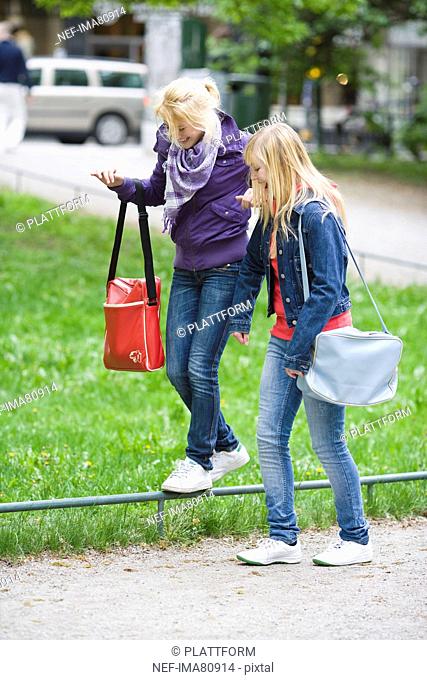 Two teenage girls walking through park