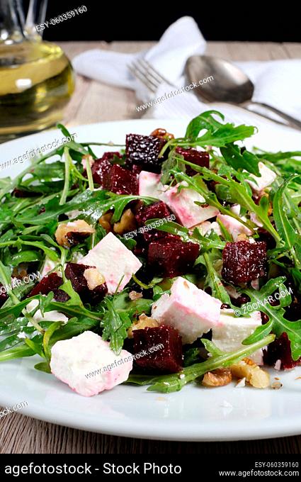 Salad from roasted beets, arugula, cheese feta, and walnuts. Vertical shot. Foreground