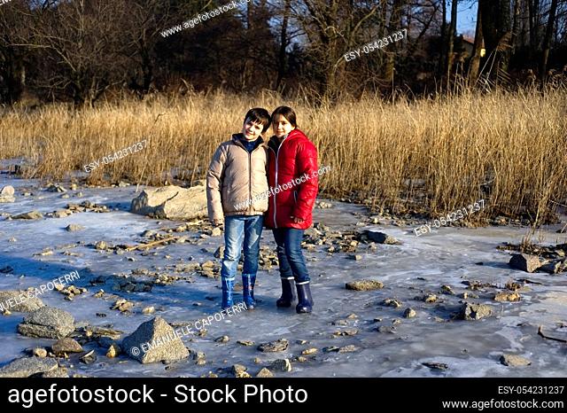 Children, siglings, portrait at the beach of the lake in winter, Lake Maggiore, Ispra, Italy