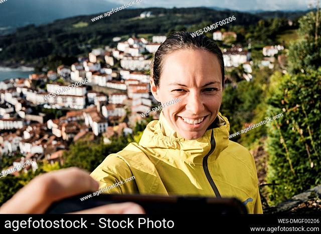 Smiling woman taking selfie through mobile phone during vacations