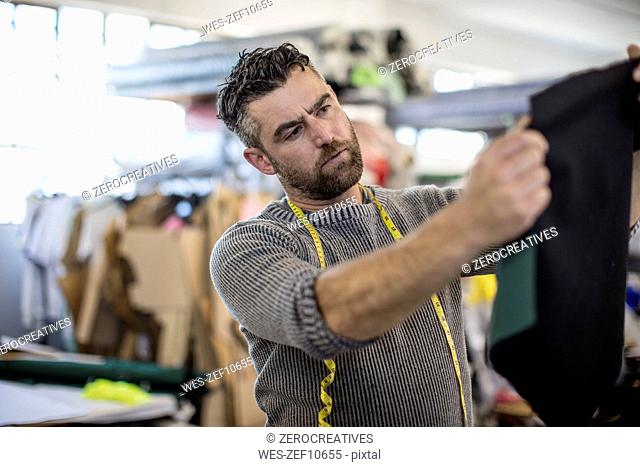 Tailor looking at clothing sample in workshop