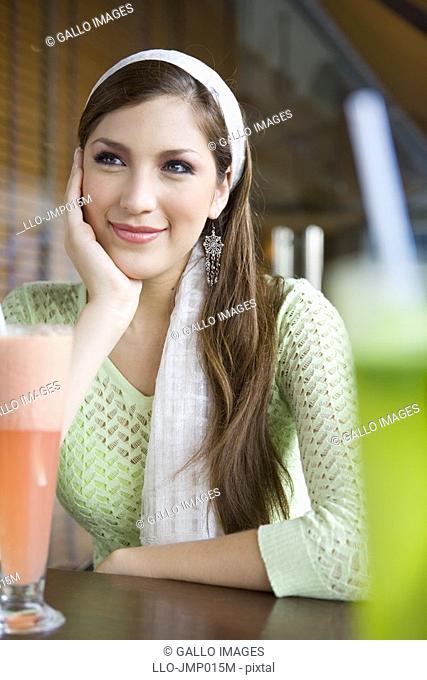 Smiling woman having smoothies with friend on outdoor patio  United Arab Emirates
