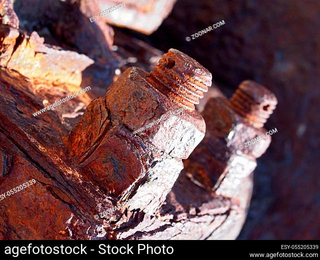 a close up of brown rusted threaded bolts and nuts on old corroded machinery