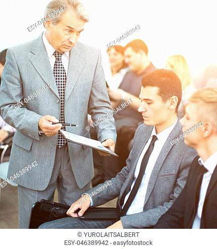 Business meeting - manager discussing work with his colleagues holding documents