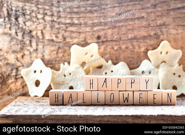 Words Happy Halloween on wooden cubes with group of scary ghost on wooden background, autumn mood horror halloween concept with witch hat modern design
