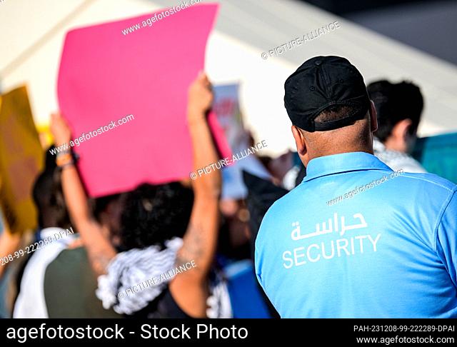08 December 2023, United Arab Emirates, Dubai: A security guard stands behind protesters on the EXPO grounds in Dubai. The main topics at this year's UN Climate...