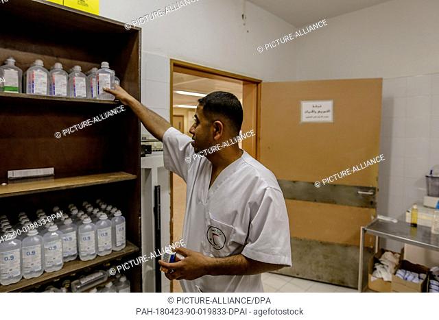 A medical staff member sorts saline solutions on the shelves of a drawer, amid major shortages of essential medicines for the wounded