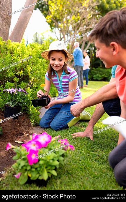 Vertical picture of caucasian family spending time together in the garden, planting