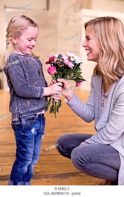Young girl giving mother bunch of flowers