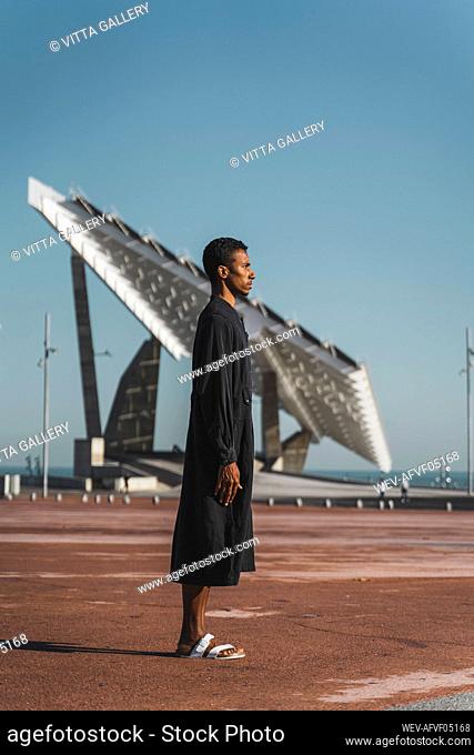 Young man wearing black kaftan under blue sky