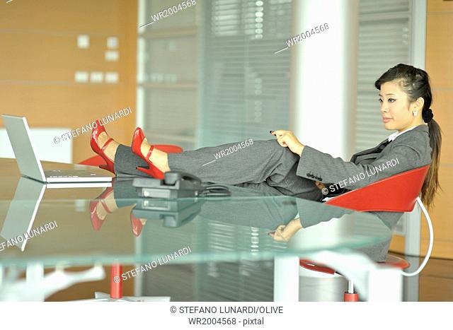 Relaxed Chinese businesswoman, shoes on her desk