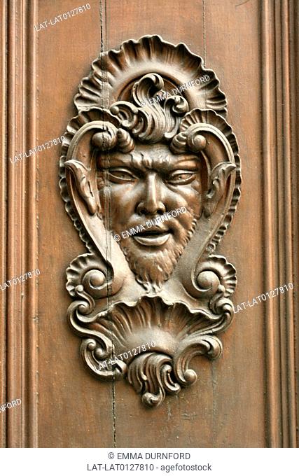 Historic buildings in the old town of Valencia have ornamental features on the exterior, Carved panel of a mythical fawn on a door