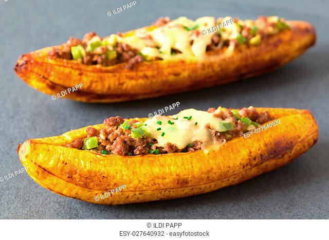 Baked ripe plantain stuffed with mincemeat, olive, green bell pepper and onion, cheese on top, sprinkled with chives, a traditional dish in Central America...