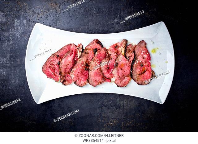 Traditional Italian barbecue dry aged wagyu roast beef steak sliced as close-up on a white plate