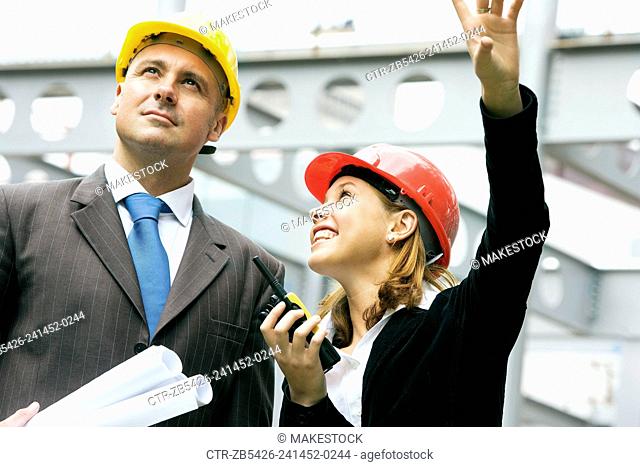 Young woman and construction Manager on a construction site wearing a hard hat and using a walkie talkie