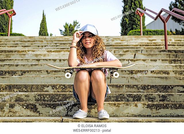 Girl with skateboard sitting on steps