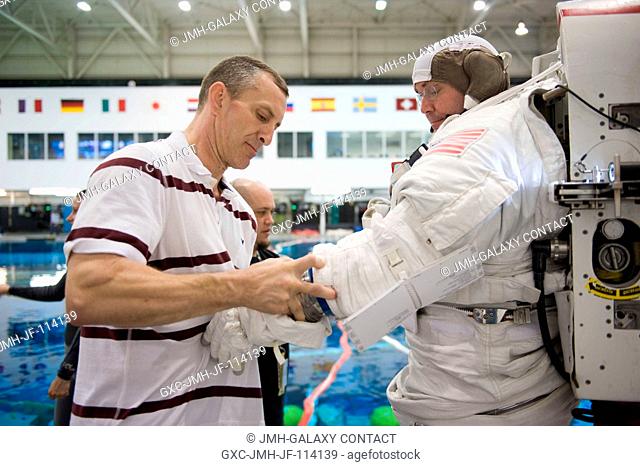 Astronaut Mike Foreman, STS-129 mission specialist, dons a training version of his Extravehicular Mobility Unit (EMU) spacesuit in preparation for a spacewalk...