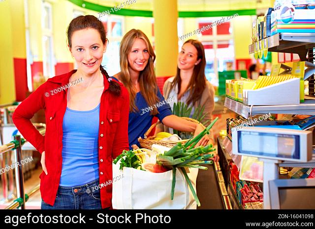 Ältere lächelnde Frau mit Einkaufskorb steht an Supermarkt-Kasse an