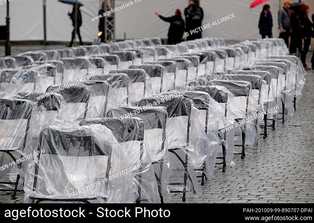 09 October 2020, Saxony, Leipzig: Folding chairs wrapped in foil are placed in the Nikolai churchyard during drizzle. With a prayer for peace
