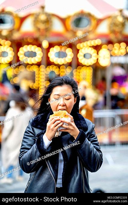Woman eating burger at amusement park