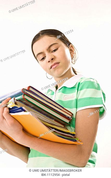 Irritated girl carrying a pile of exercise books and school books