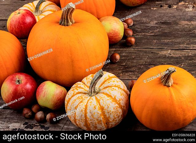 Autumn harvest still life with pumpkins , apples , hazelnuts on wooden background , top view