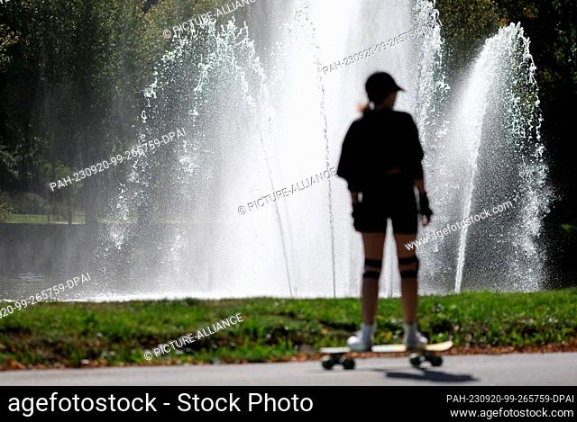 20 September 2023, Saxony, Leipzig: A skater rides past a water fountain in Clara Zetkin Park. For the weekend, meteorologists expect early autumn weather