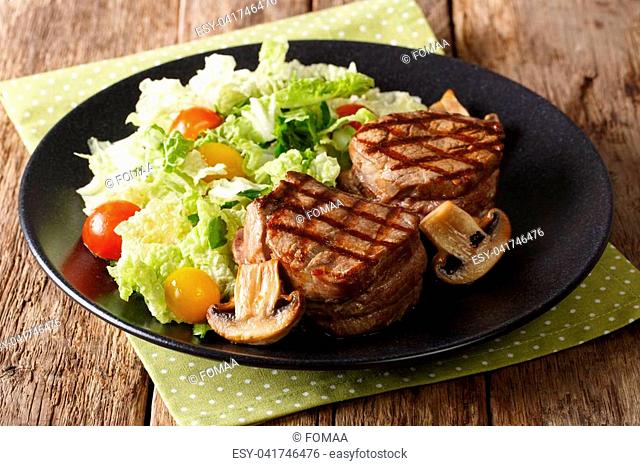 Healthy food: filet mignon steak with mushrooms and fresh vegetable salad close-up on a plate. horizontal