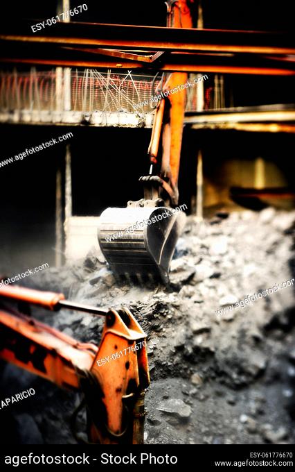 Excavator removing rocks and dirt at a construction site, for the realization of this image has been used Tilt and Shift lens blurring the sides