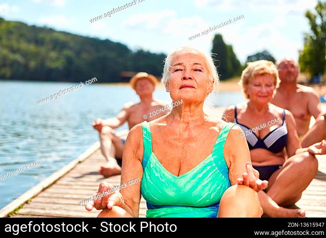 Senioren Gruppe bei einer Yoga Meditation am See in einem Wellness Workshop