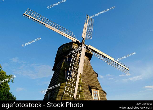 Retro wooden mill with windows and wings against blue sky