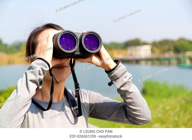 Woman use of the binoculars at forest