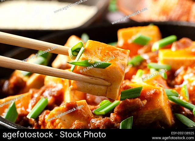 Mapo tofu dish of soybean curd piece being held in chopsticks