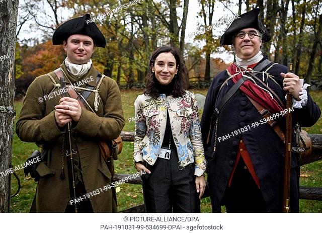 31 October 2019, US, Boston: Actress Sibel Kekilli walks through the Minute Man National Historical Park between two rangers wearing historical militia uniforms...