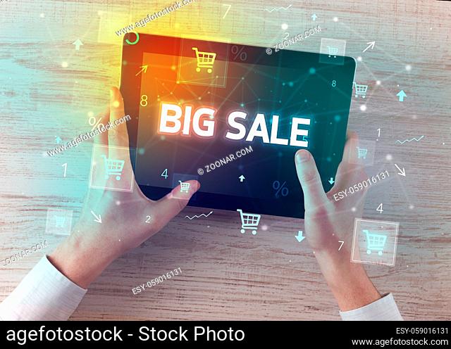 Close-up of a hand holding tablet with BIG SALE inscription, online shopping concept