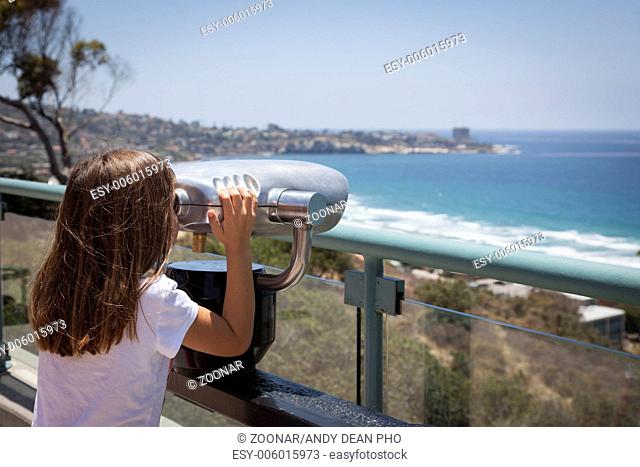 Young Girl Looking Out Over the Pacific Ocean with Telescope