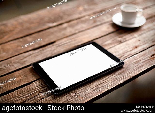 Digital tablet computer with isolated screen on wooden table with cup of coffee