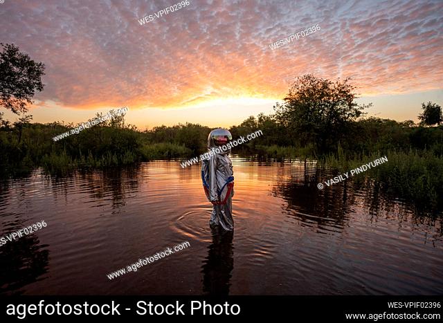 Spacewoman walking in water at sunset