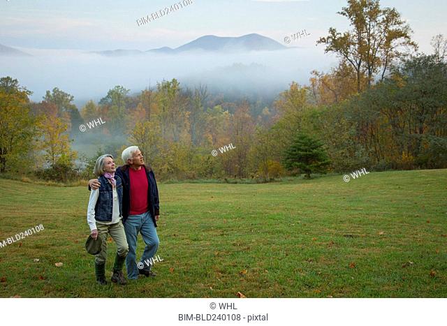 Older Caucasian couple walking in field