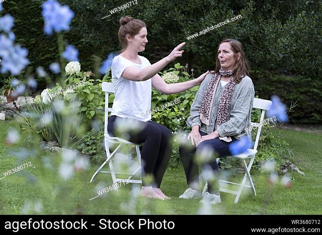 Woman and female therapist seated at an alternative therapy session in a garden