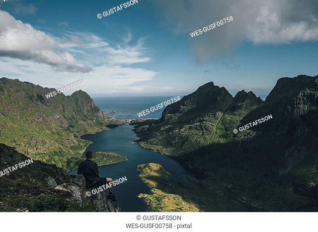 Norway , Lofoten, Traveller sitting on rock, looking over Agvatnet lake